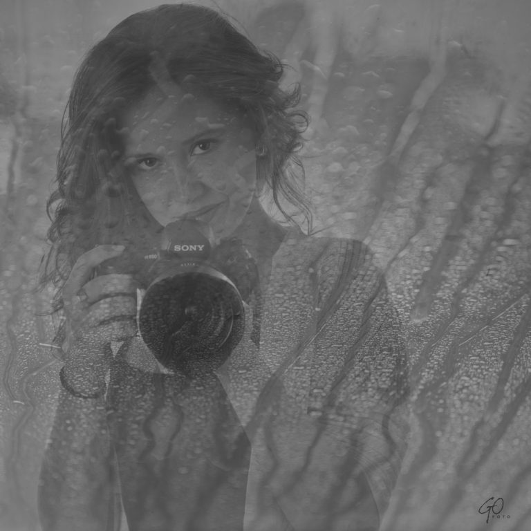 Jonge vrouw met fotocamera achter beslagen glas