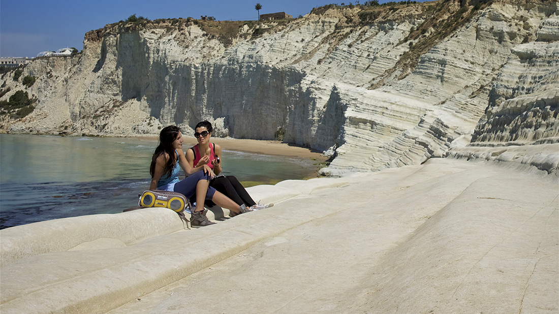 Twee meisjes zitten te praten aan het strand bij blog over vakatiefotografie 7 tips