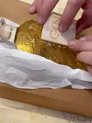 Labeling the Gin Cask Aged Gin bottle by hand