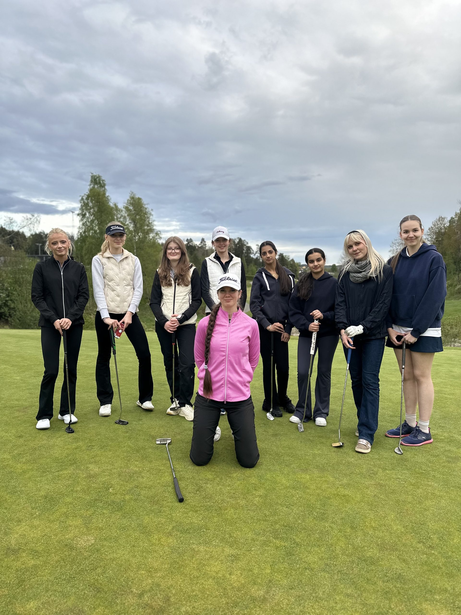 Jenter i Birdie Girl Crew omkranser sin trener i rosa jakke.