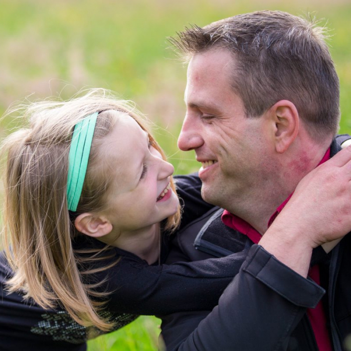 Vater und Tochter umarmen sich auf Blumenwiese