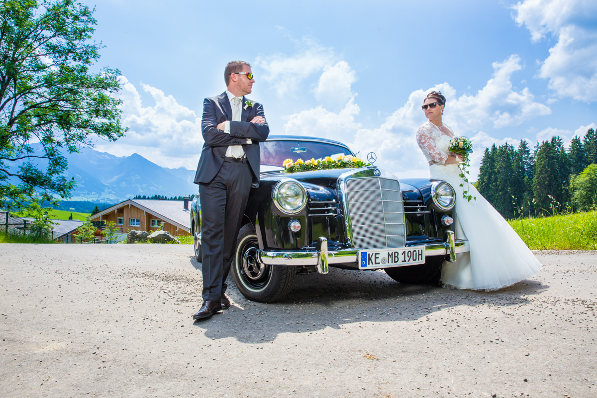 Hochzeitspaar lehnt an Oldtimer