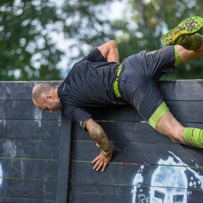 Sportler springt über eine Hinderniswand