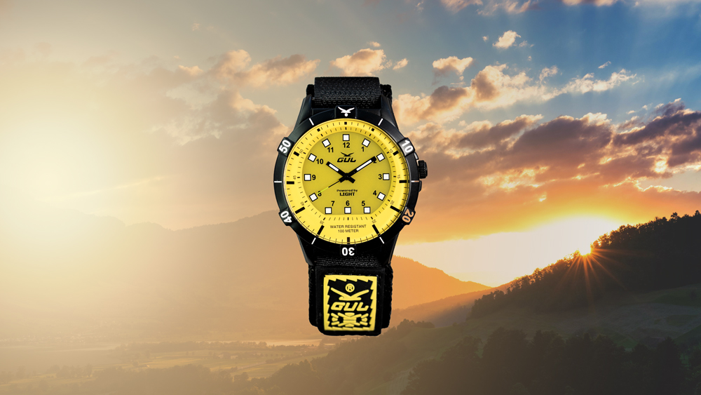 Gul watches wrist watch yellow and black against sunset sky over mountains