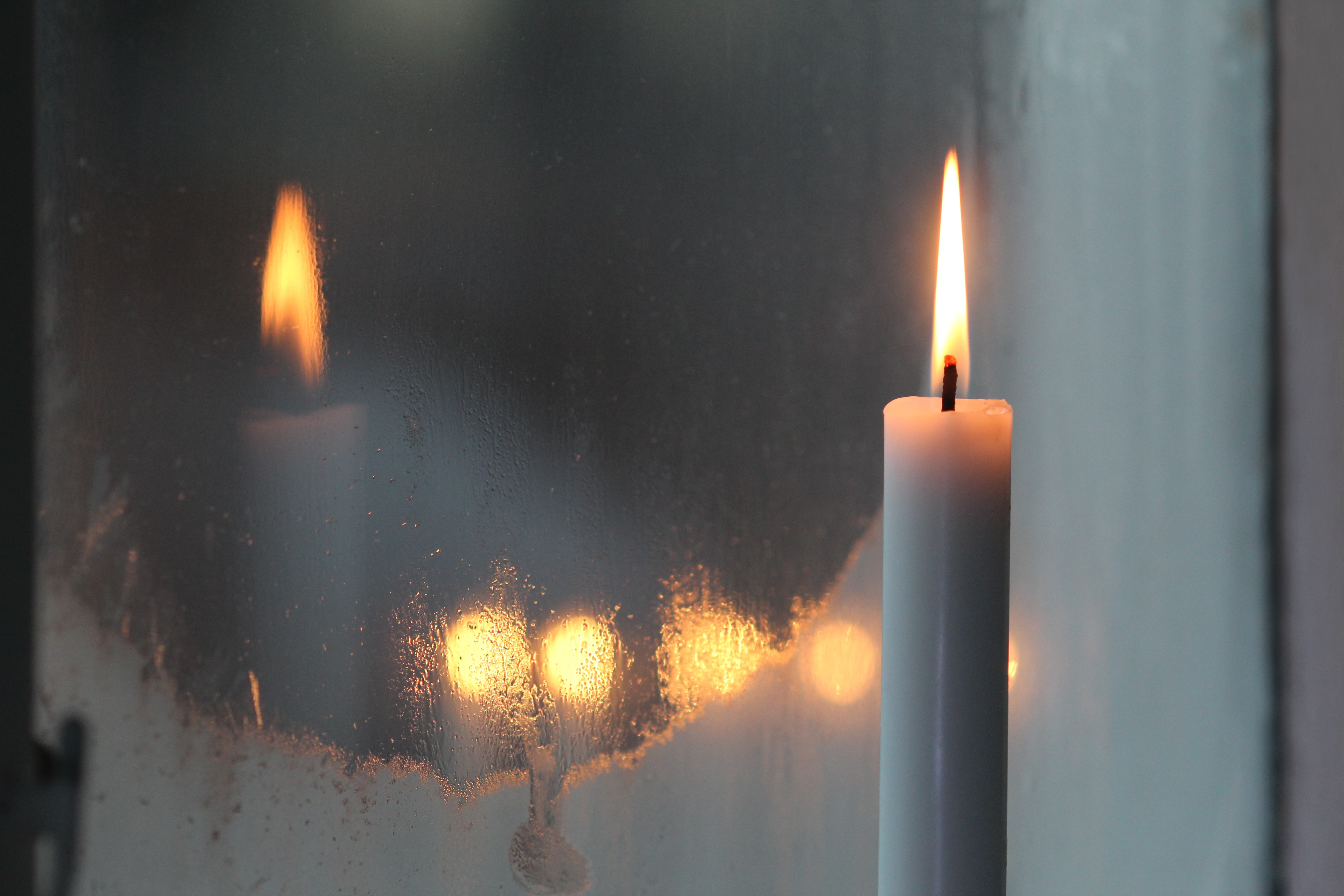 Candle burning in snowy window