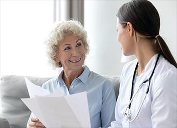 This photo shows a content patient holding paper, making eye contact with a medical professional. It is being used to show the consultation process where we provide peace of mind over any concerns patients might have.