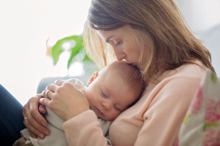 Young mother, holding tenderly her newborn baby boy, close portrait