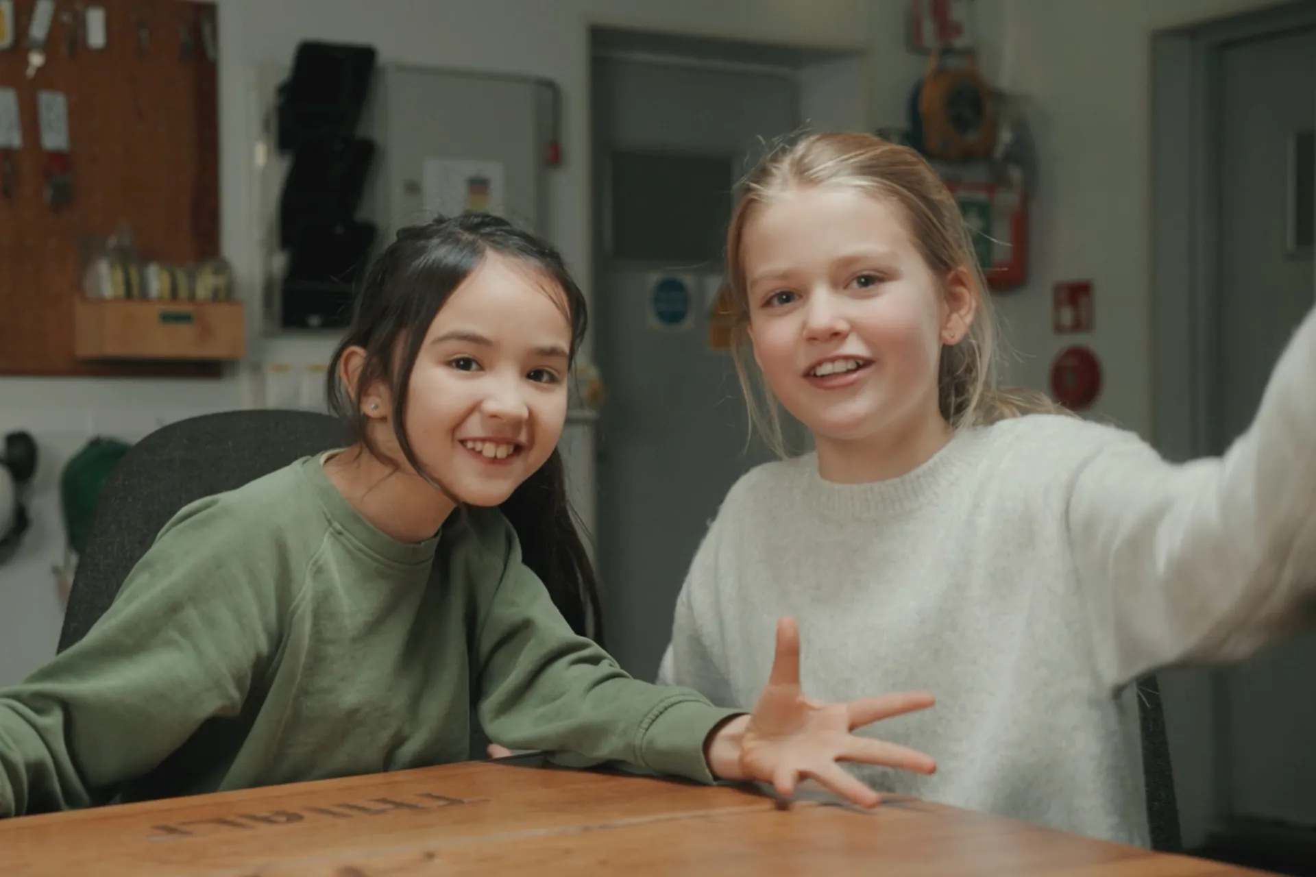 Twee kinderen met groen en witte trui aan kijken olijk in de camera