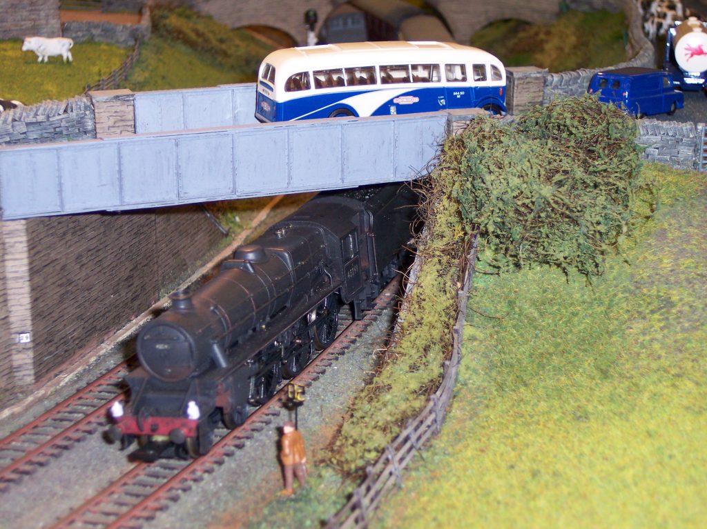 Black 5 hauled train and motor coach at the road overbridge.