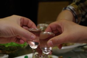 To personer skåler med små glass under et måltid i Kina, som symbol på relasjonsbygging og samarbeid.