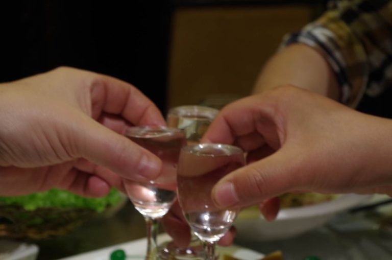 To personer skåler med små glass under et måltid i Kina, som symbol på relasjonsbygging og samarbeid.