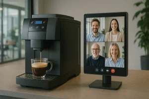 En moderne kontorkaﬀemaskin brygger kaffe i et glasskrus på en benkeplate. Ved siden av står en videoskjerm som viser fire personer i et videomøte. Bildet illustrerer en hybrid arbeidshverdag hvor ansatte kan ha uformelle samtaler digitalt – som om de sto ved samme kaffemaskin.