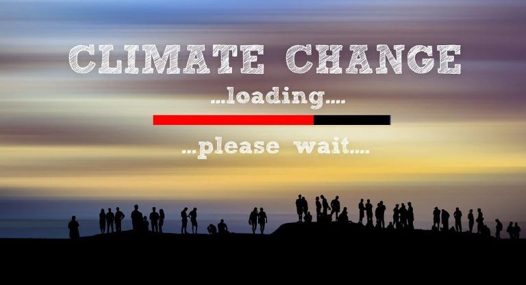 En silhuett av en gruppe mennesker står på en høyde mot en fargerik himmel med horisontale striper i blått, gult og lilla. Teksten 'CLIMATE CHANGE' er skrevet i store, hvite blokkbokstaver øverst, med en lastelinje under som viser '...loading...' i rødt og svart. Under står '...please wait...,' noe som antyder at klimaendringene er en pågående prosess.