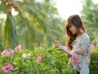 woman wearing white pink and green floral dress holding pink bougainvillea flowers