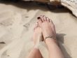 human feet on white sand during daytime