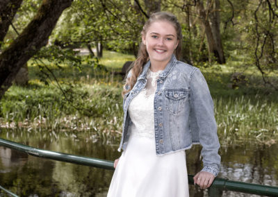 Konfirmationsbilleder af pige lænende op ad rækværket på en bro