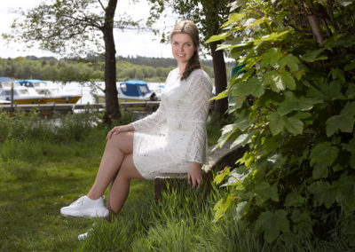 Konfirmationsbilleder af pige siddende på en træbjælke