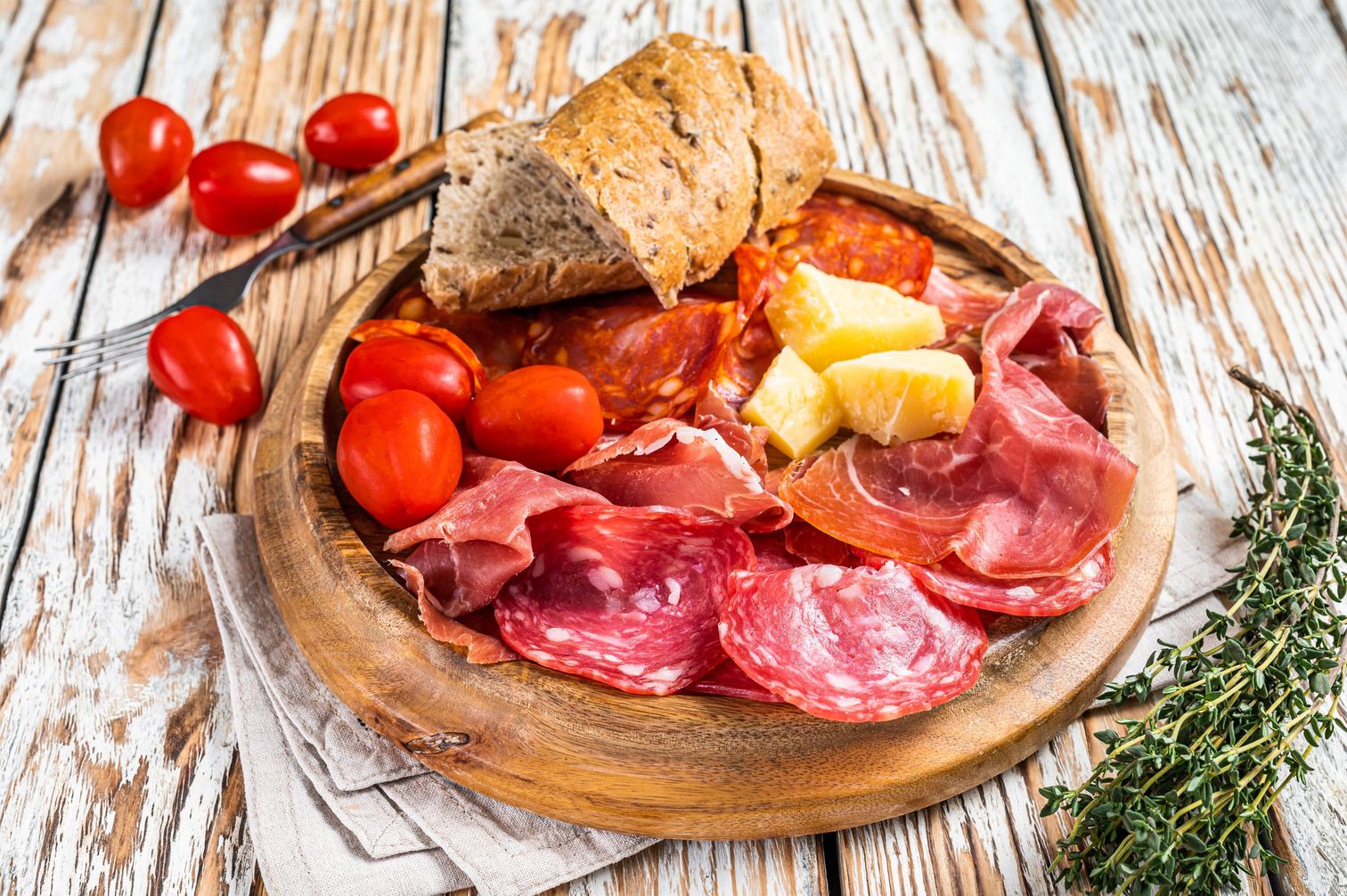 Cold meat plate, charcuterie traditional Spanish tapas on a wooden board. White wooden background. Top view.