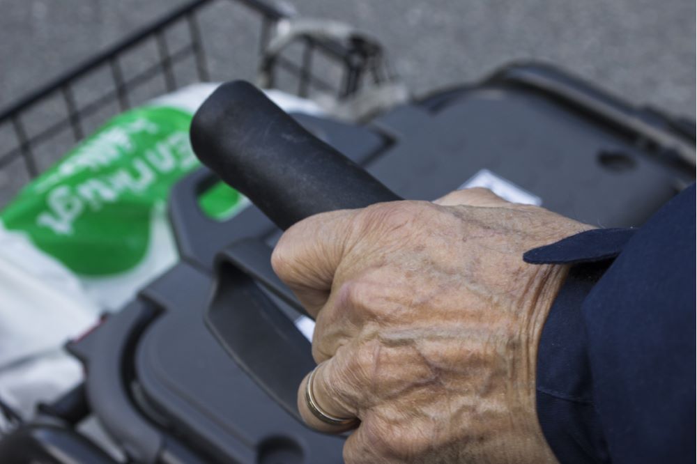 Äldre persons hand håller i en rollator.