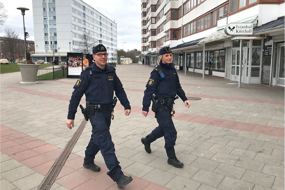 Två patrullerande poliser på ett torg.