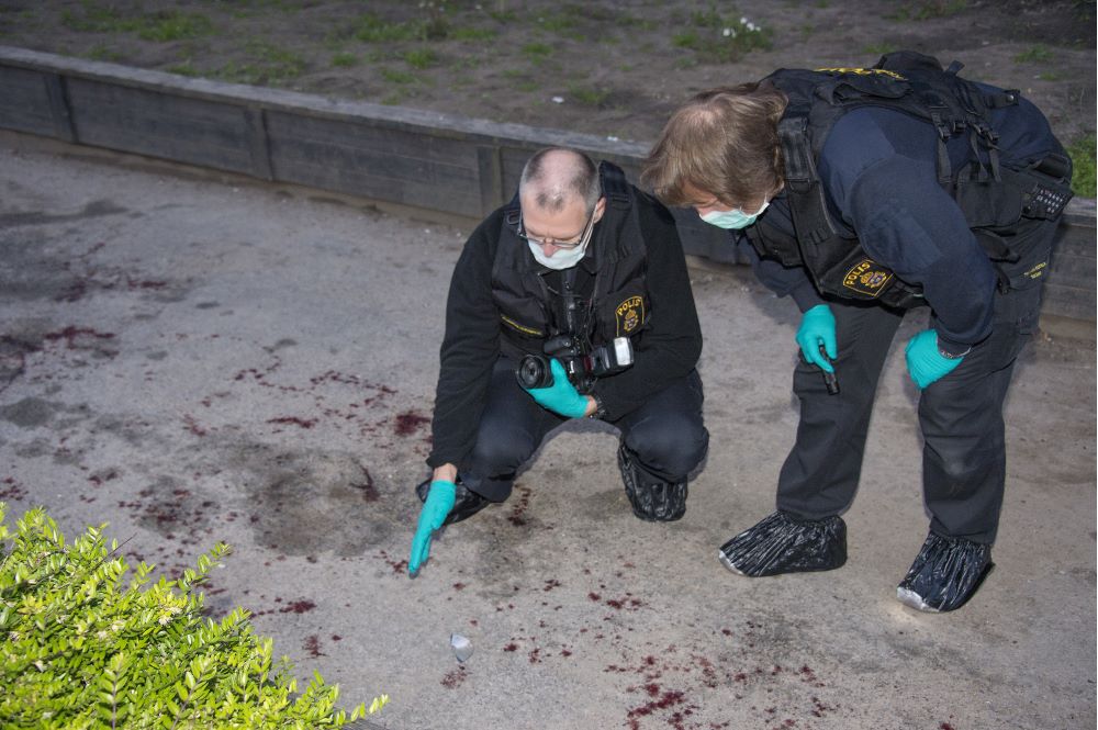 Två poliser undersöker en brottsplats med blodspår.