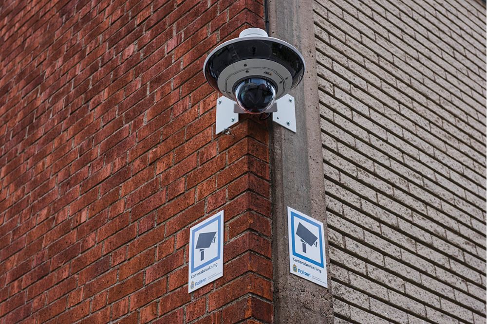 Övervakningskamera monterad på husvägg i tegel.