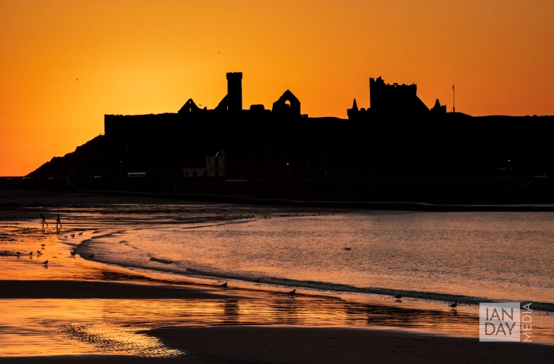 The sun sets behind Peel Castle on the Isle of Man.