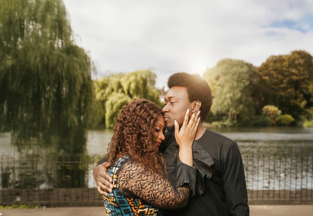 Couple embracing by serene lake.