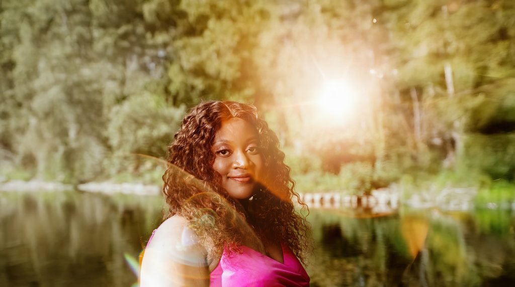 Woman in pink dress by water.