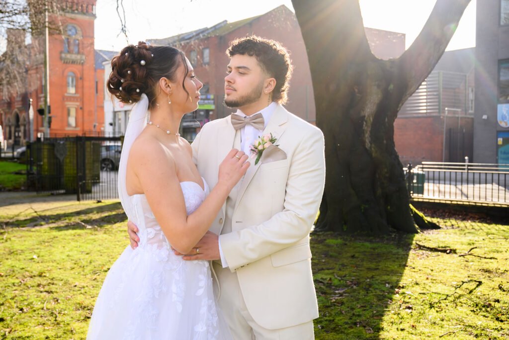 Bride and groom embracing in a sunlit park in West Bromwich.