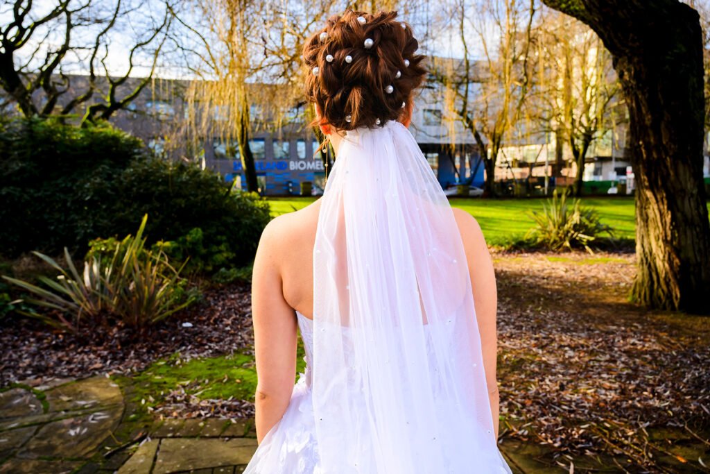 Back view of the bride's dress and veil as she walks towards the groom.