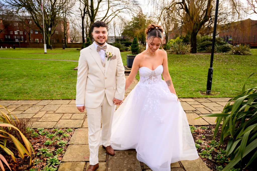 Newlyweds walking hand-in-hand outside the historic Sandwell Register Office.