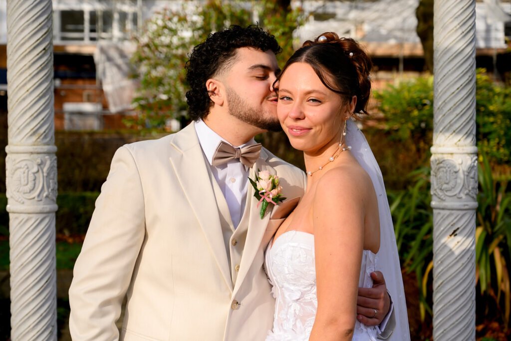 groom is kissing on brides forehead while bride is looking away.