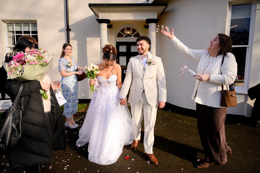 Bride and groom walking out of Sandwell Register Office entrance.