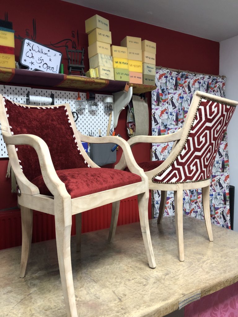 Twee stoelen op de werktafel geherstoffeerd in rode stof