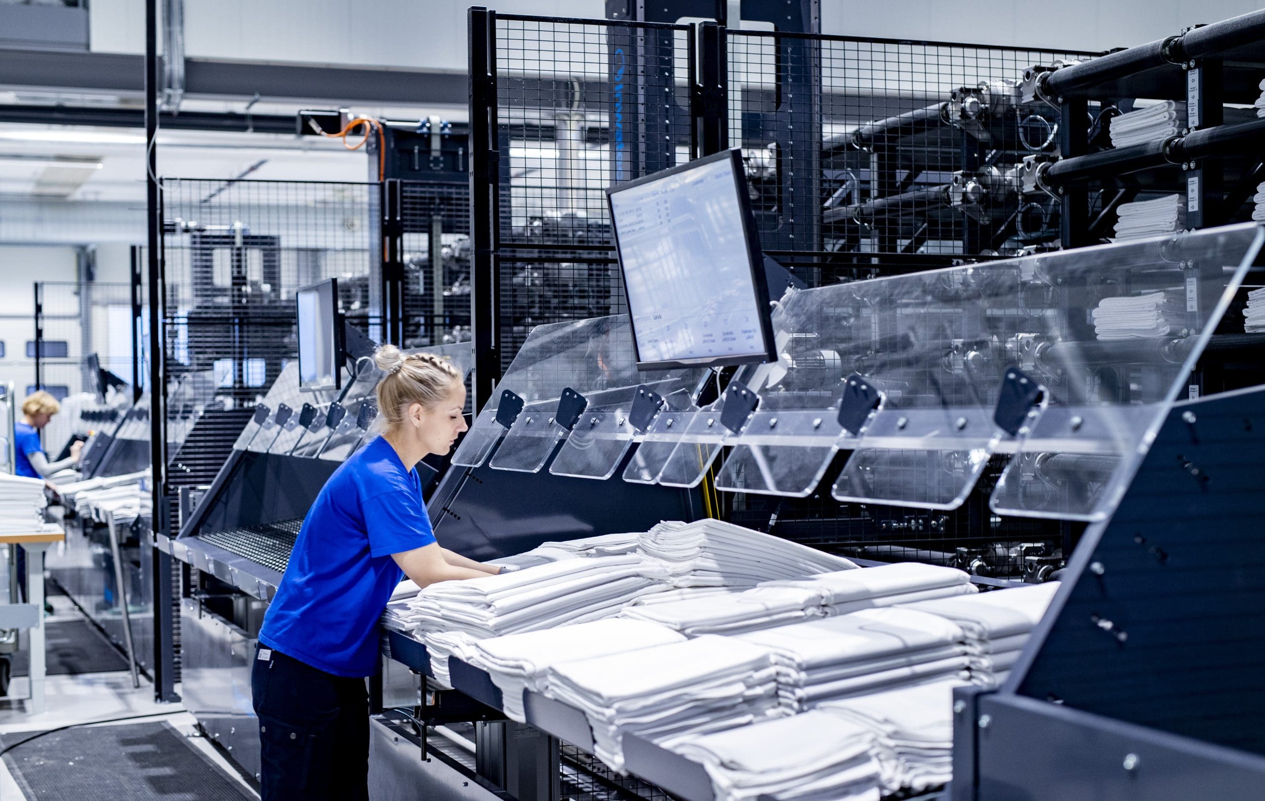 Nor Tekstil employee working to remove folded laundry from Inwatec's machine