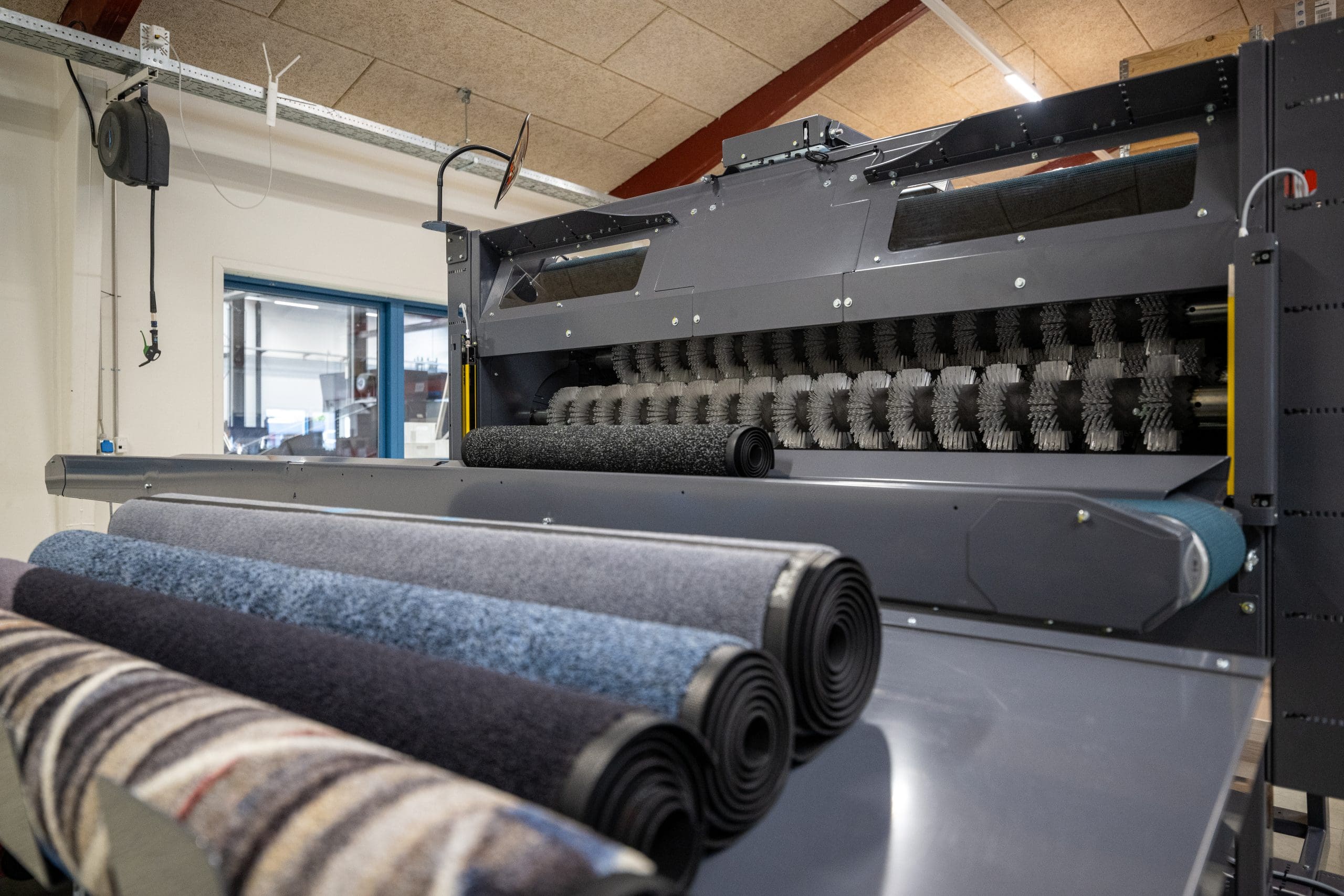 Close-up image of the Inwatec Typhoon Mat Roller machine where you see the mats coming out of it rolled up nicely.