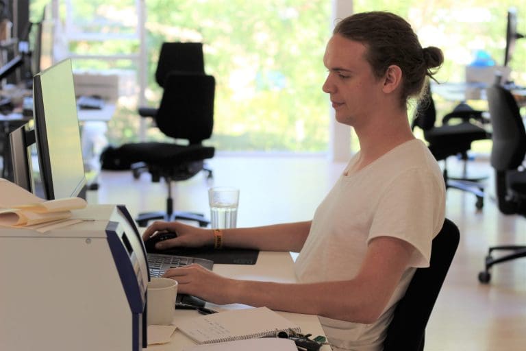 A young man sitting in front of a computer working with something for Inwatec.