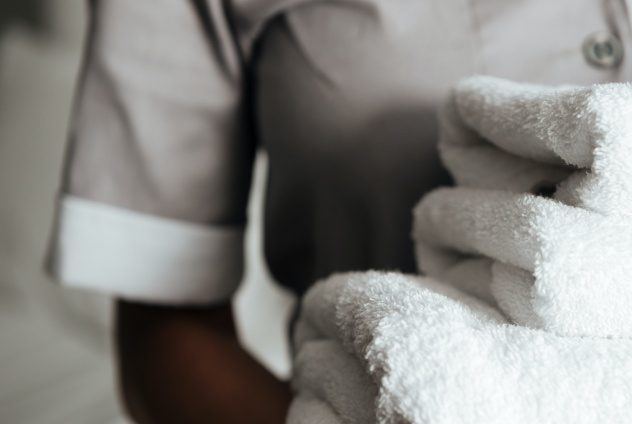 Maid carrying some folded towels.