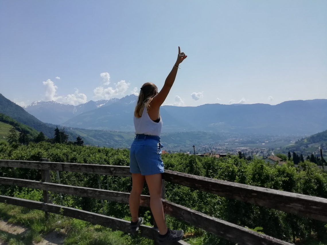 Woman standing on railing one hand stretched upwards