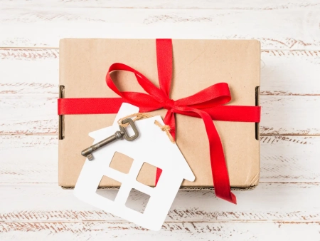 close-up-house-key-tied-with-red-ribbon-brown-gift-box-painted-wooden-desk (1)