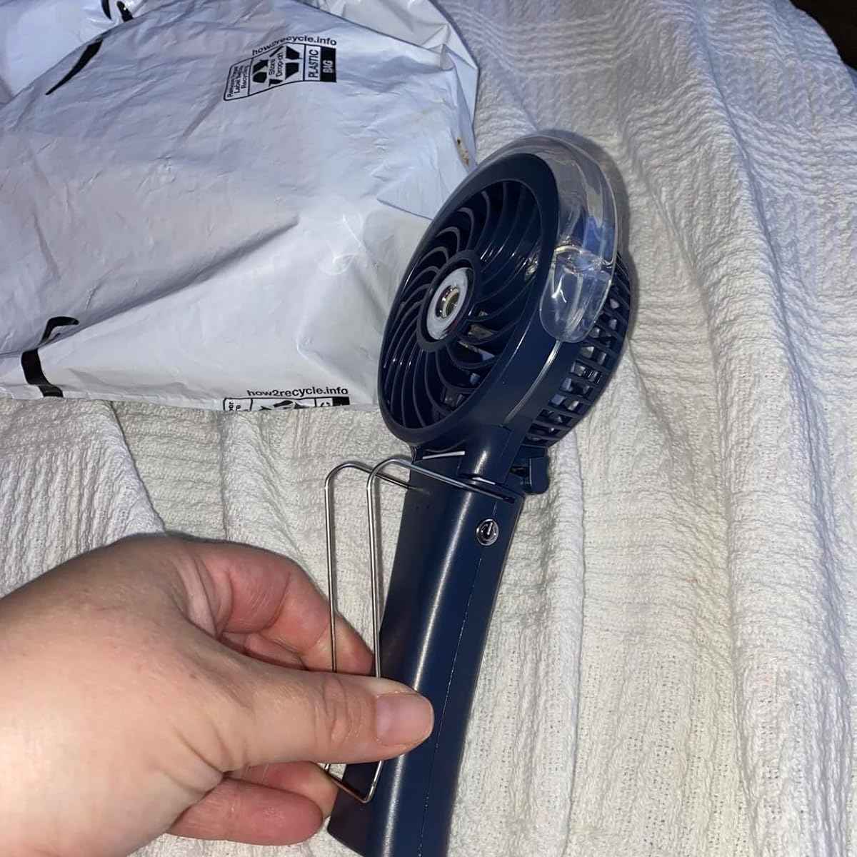 a hand holding a blue fan