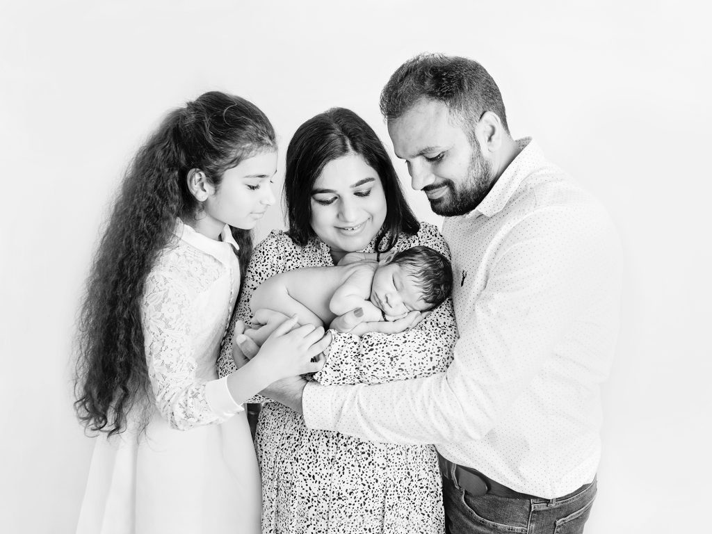 newborn and family photography with 7 year old sister black and white photo of everyone looking at baby newborn photography edinburgh