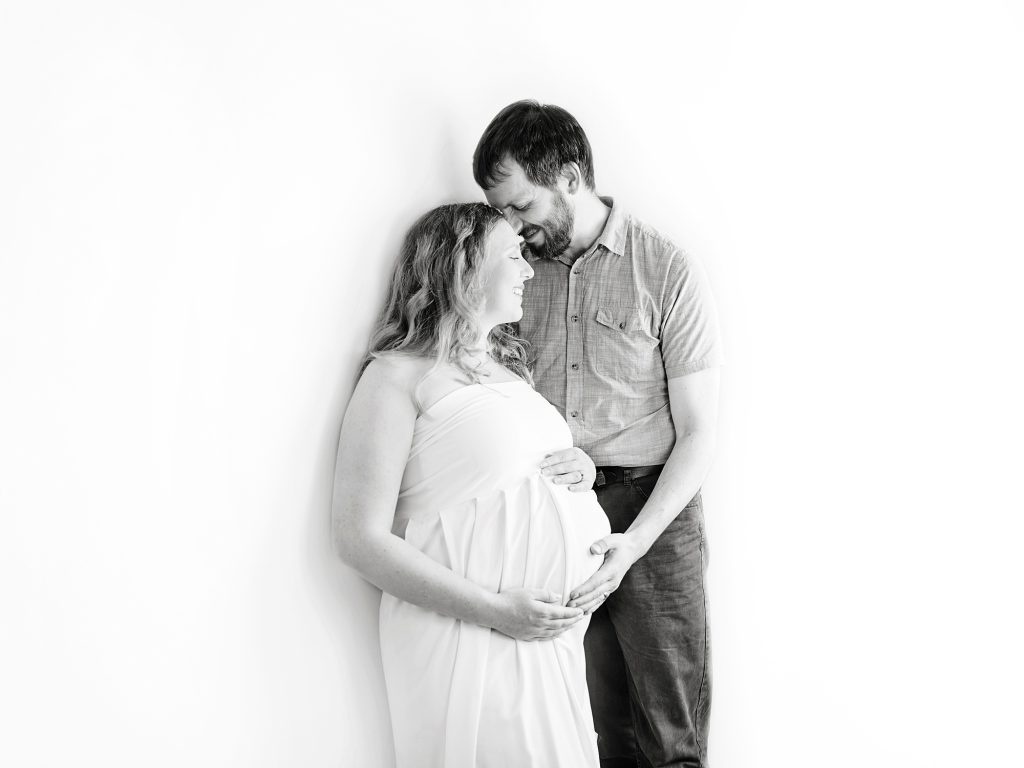 black and white maternity photo on white background with partner snuggling up maternity photography edinburgh