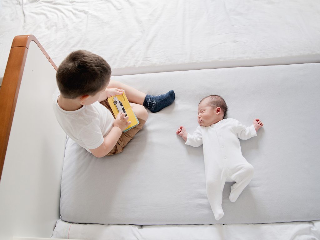older sibling with a newborn reading a book - lifestyle family photography edinburgh