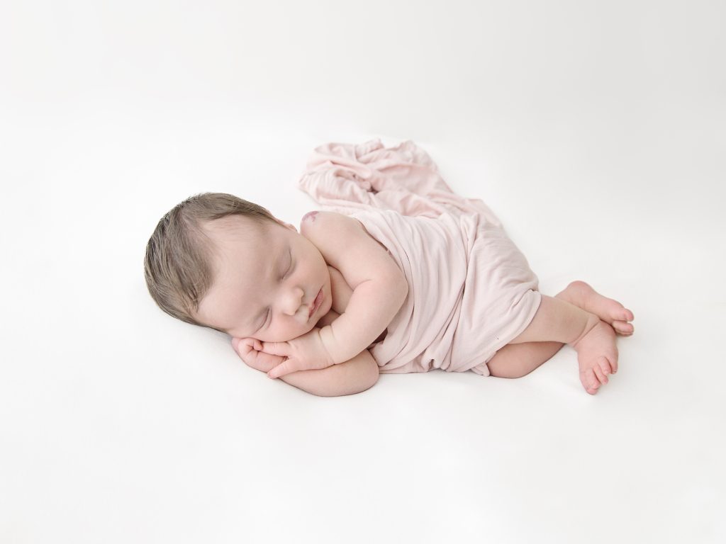 side laying pose for newborn photography on white
