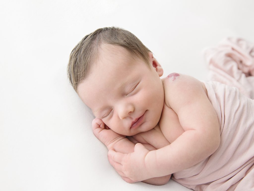 smiling newborn baby on white background