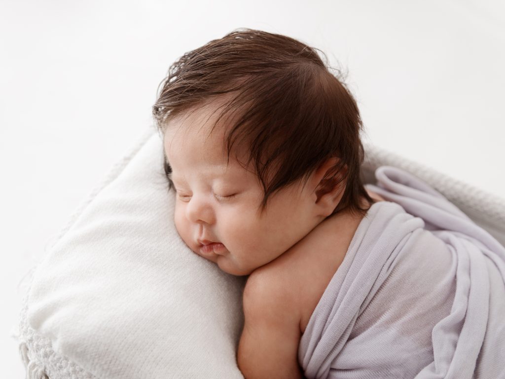 newborn posing in a basket on tummy 1 month old