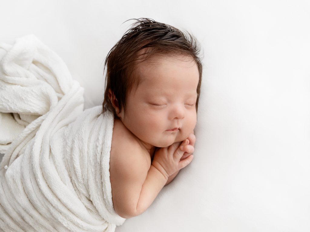 newborn baby on tummy posing all white photos