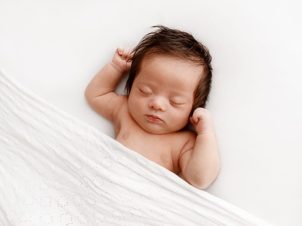 baby on his back tucked in newborn posing